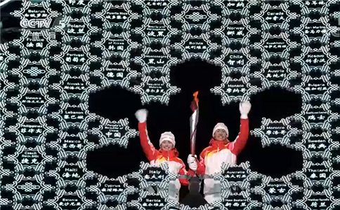 经过多位国家队运动员轮番传递，越野滑雪运动员衣拉木江和北欧两项运动员赵嘉文一起，将最*后一棒火炬插在大雪花火炬台的中心。